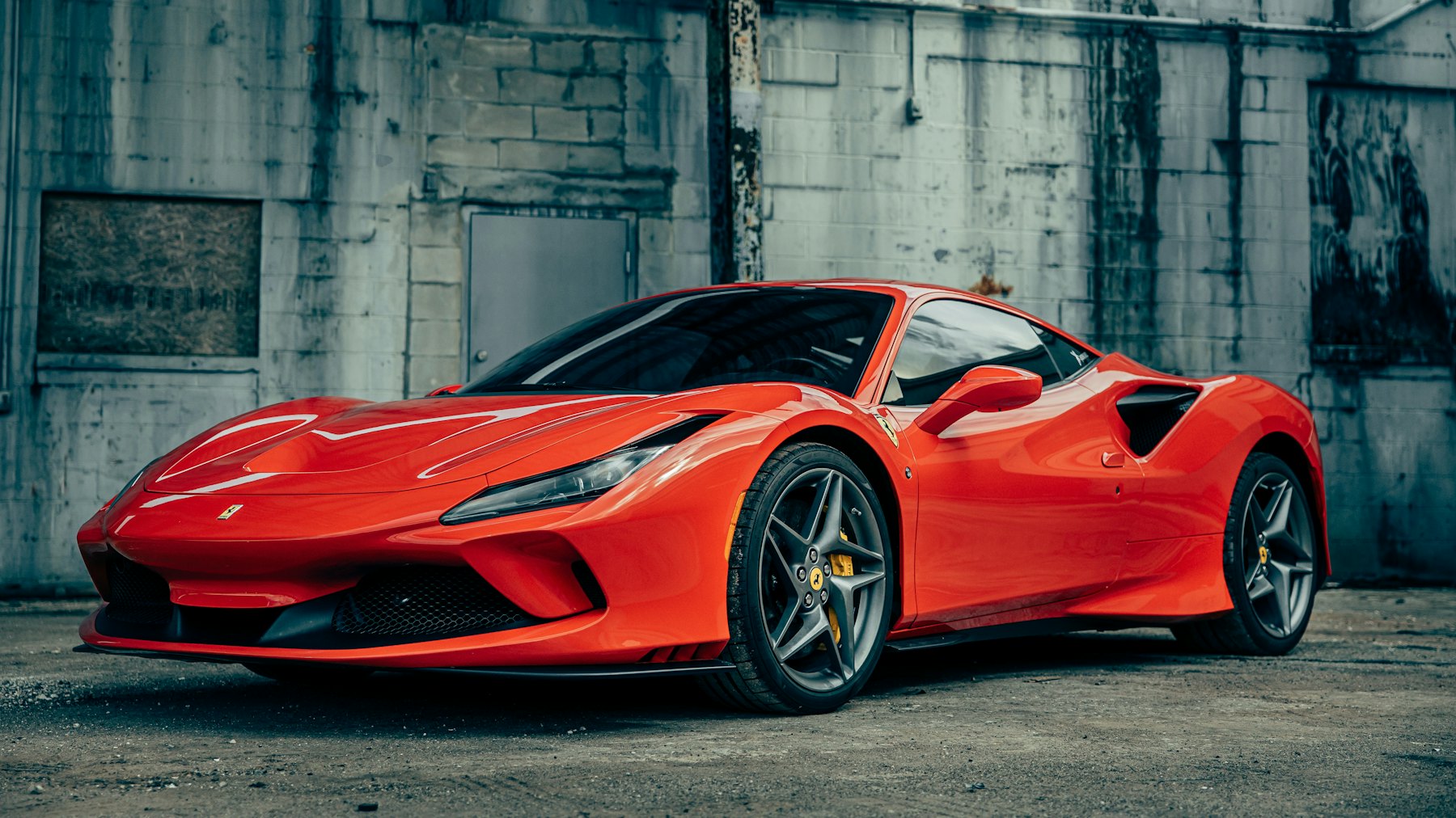 Beton duvar önünde kırmızı bir Ferrari F8 Tributo, ön çapraz açıdan