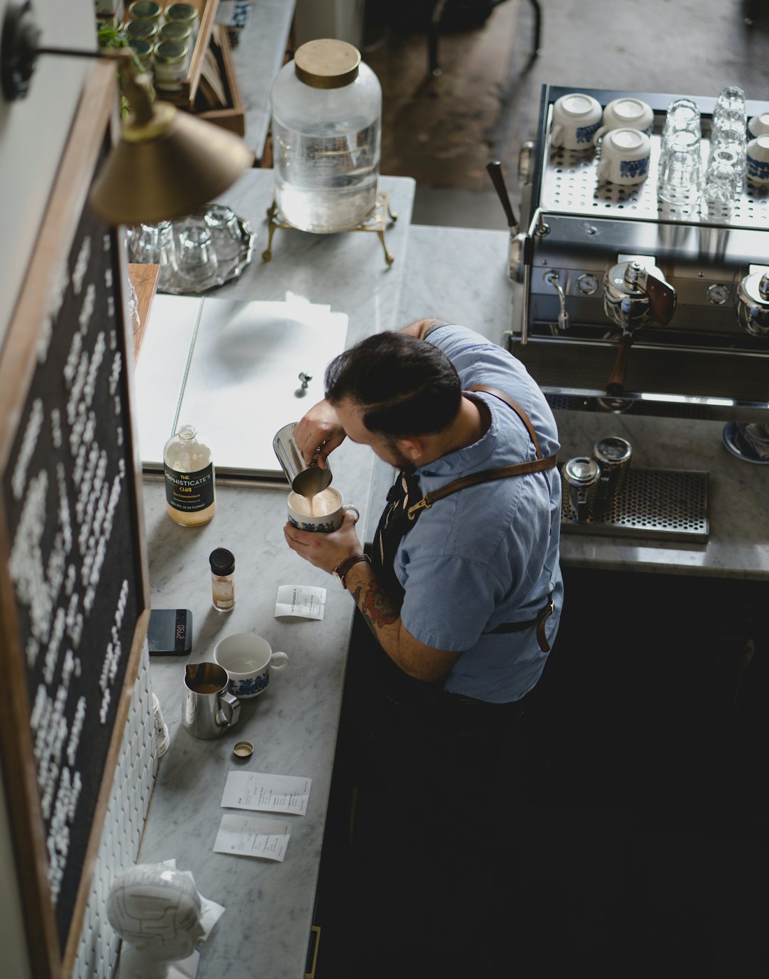 Overhead view of a barista steaming milk at a marble counter