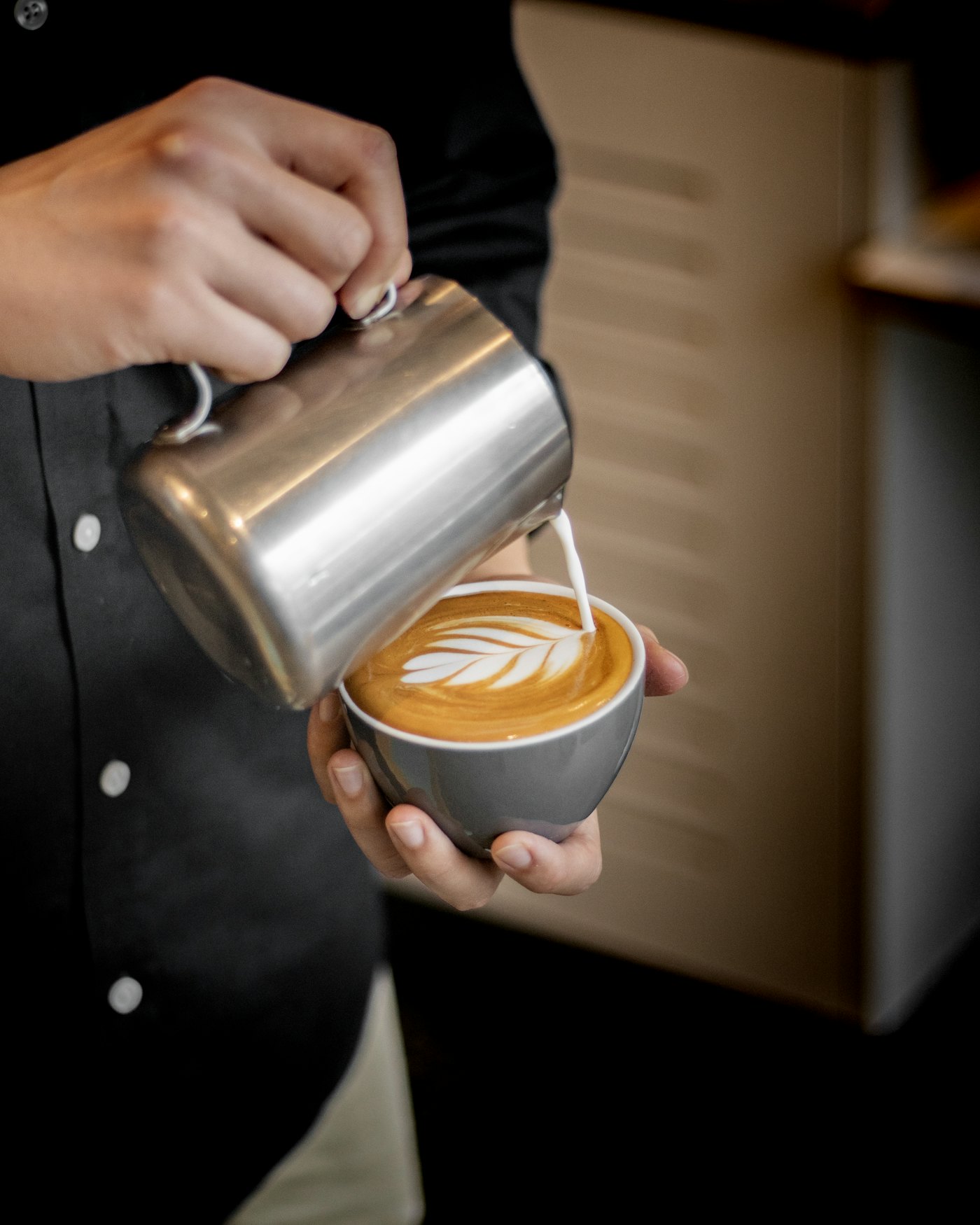 Barista pouring latte art into a ceramic cup