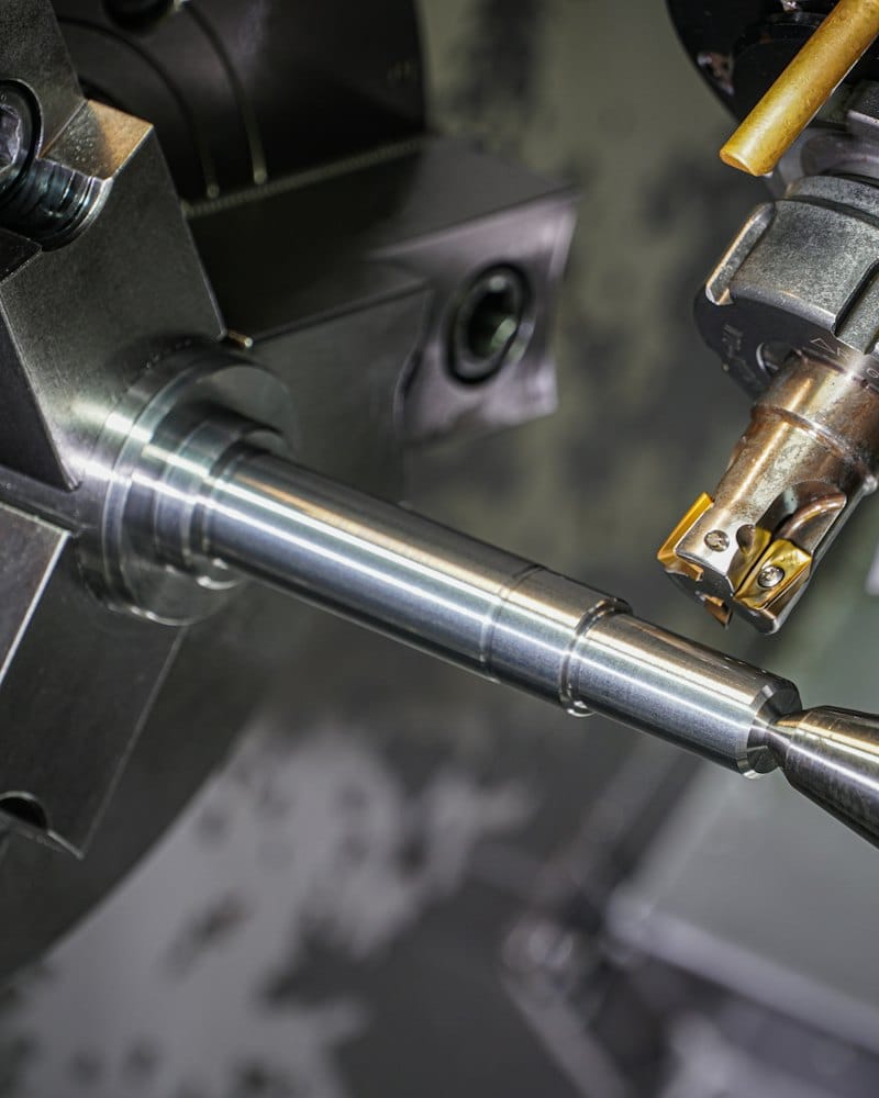 A steel shaft being turned on a lathe