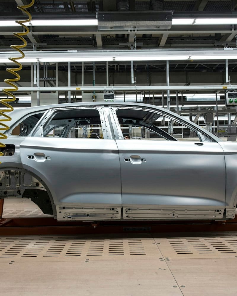 An unpainted car body moving along an assembly line