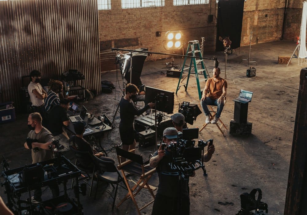A commercial film set in a large warehouse, with lights and crew