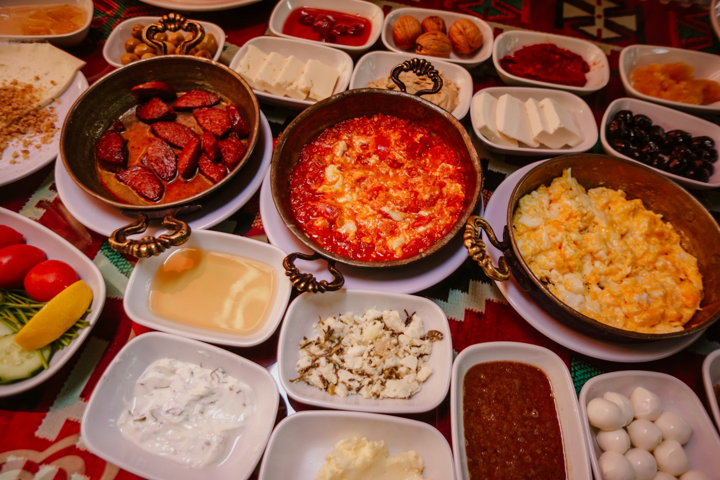A breakfast table laid with menemen, cheeses and jams