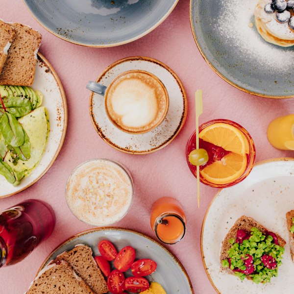 Pembe masada kahvaltı tabakları ve cappuccino