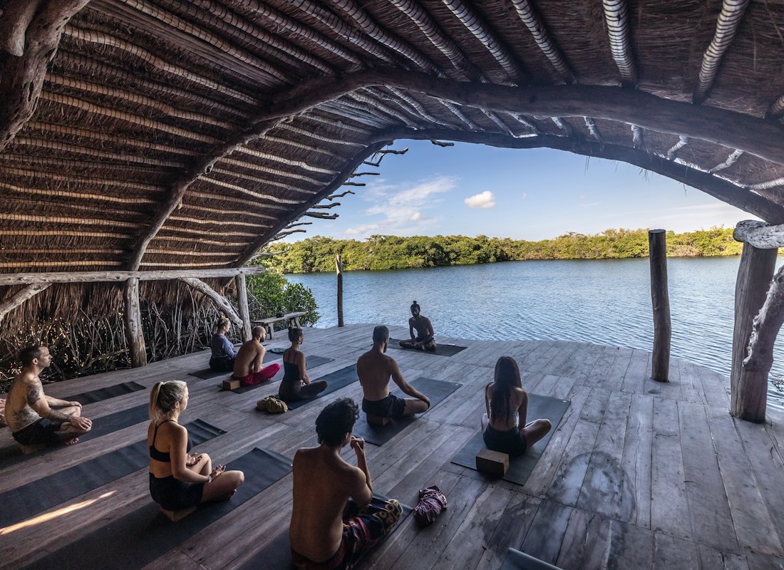 Göl kenarında ahşap bir terasta yoga yapan katılımcılar
