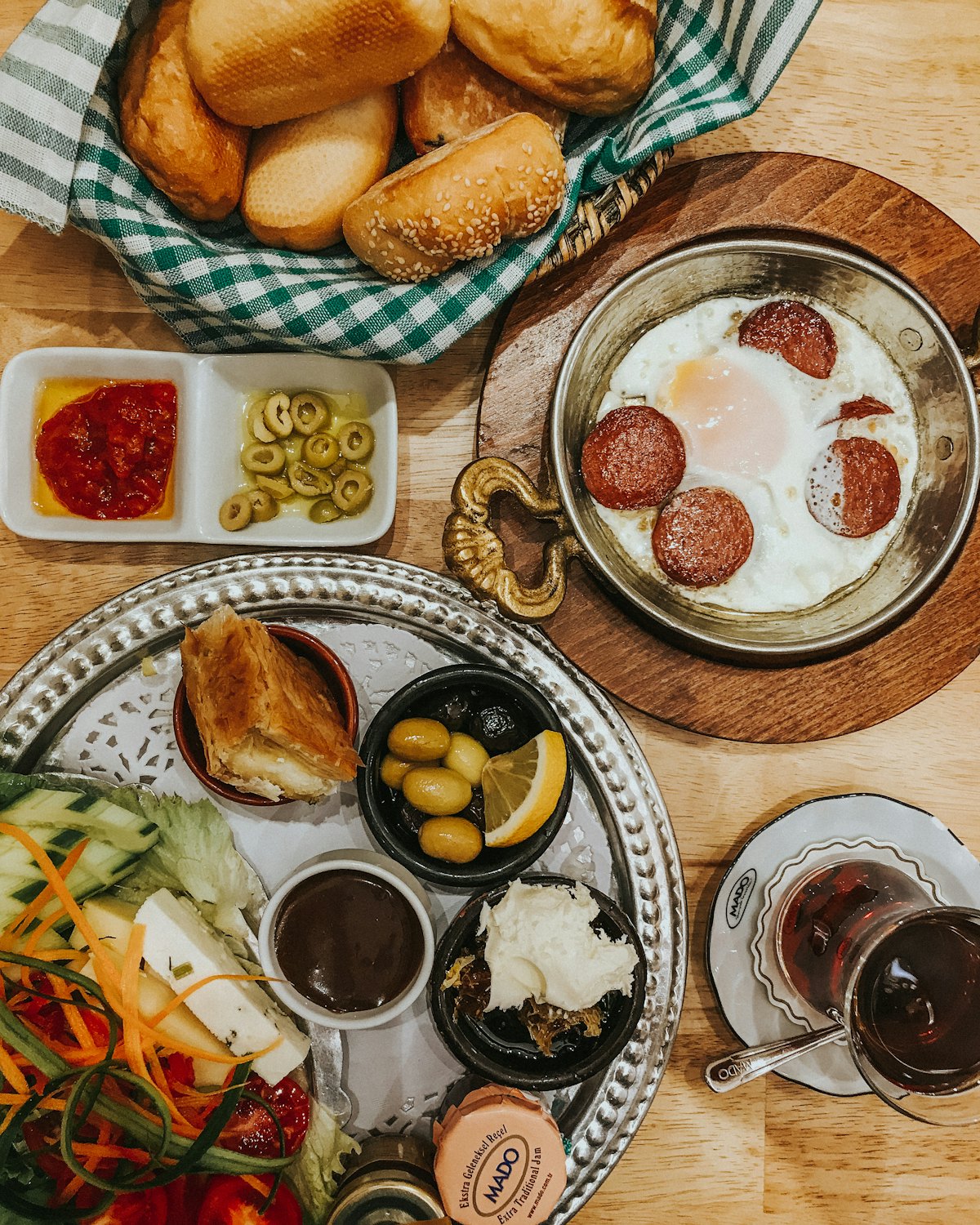 Bakır sahanda sucuklu yumurta, peynirler, zeytin ve simitle kurulmuş serpme kahvaltı sofrası