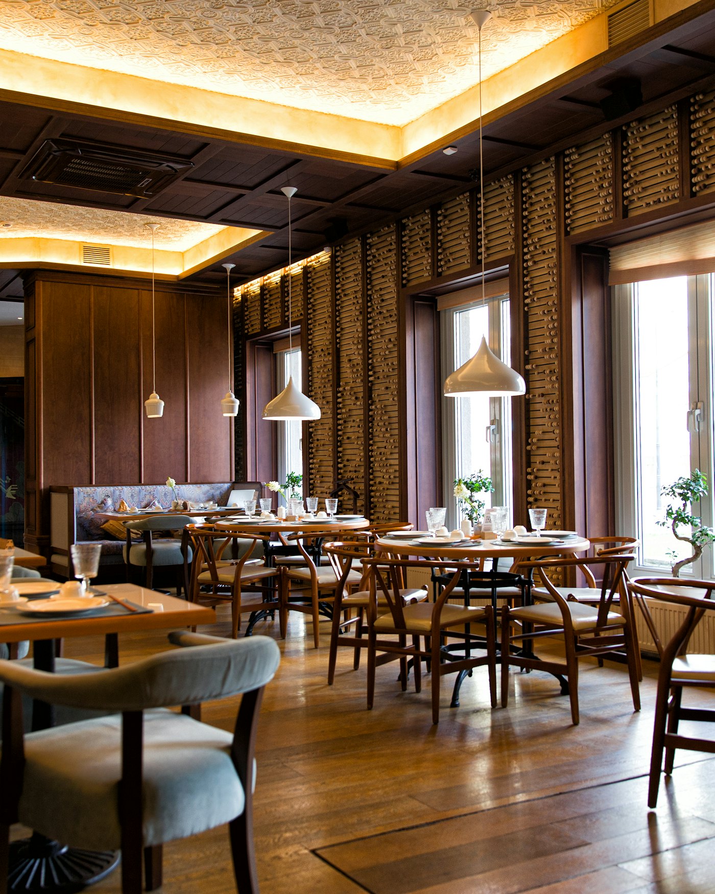 Tuğla duvarlı, sarkıt lambalı ve ahşap masalı sıcak restoran salonu