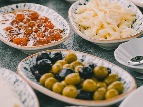 Seramik kaselerde yeşil ve siyah zeytin, çeçil peyniri ve reçel