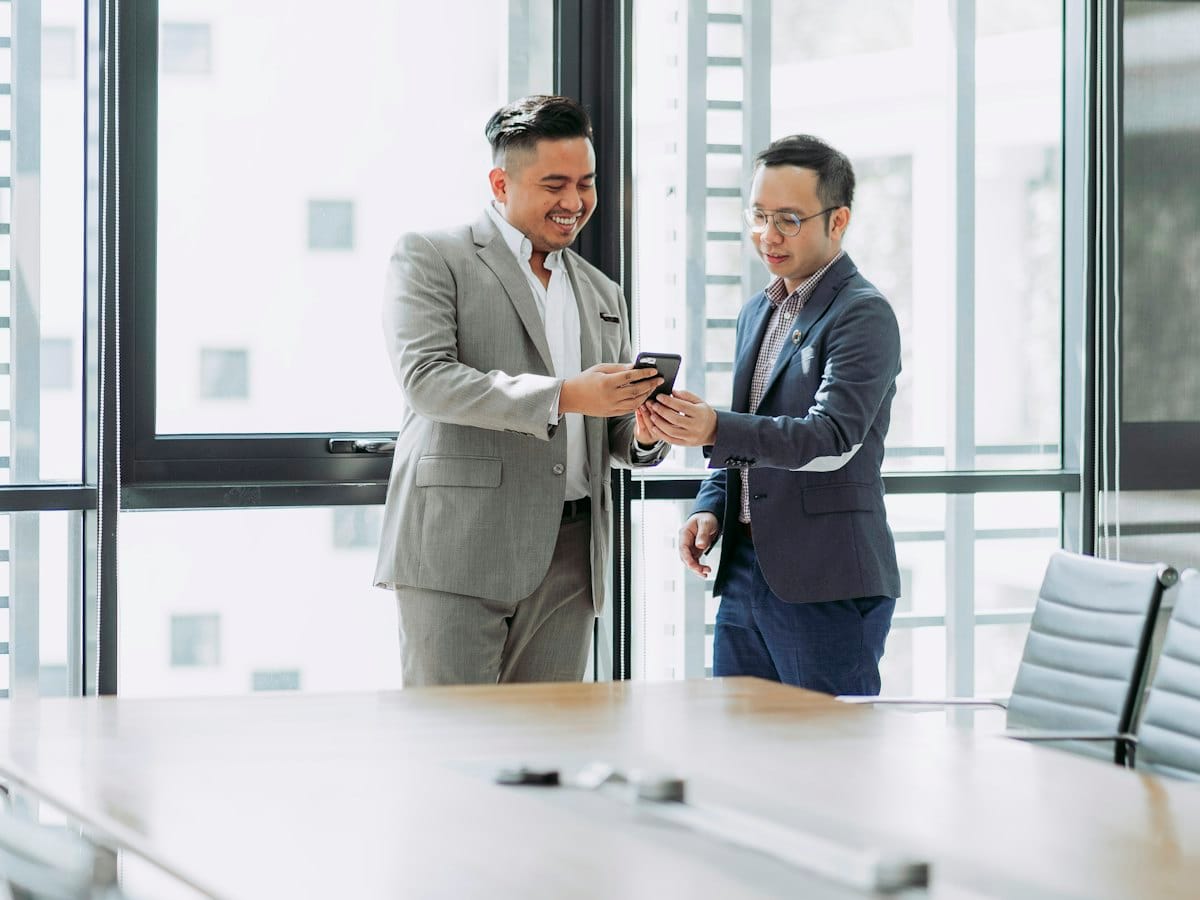 Two executives checking a press story on a phone in the office